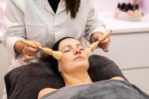 Professional beautician massaging face of customer in salon photo