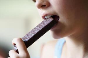 Crop unrecognizable teenage girl eating healthy protein bar photo