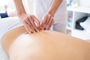 Professional masseuse massaging back of client photo