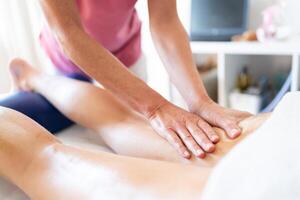 Crop masseuse rubbing oily skin of client during body massage in clinic photo