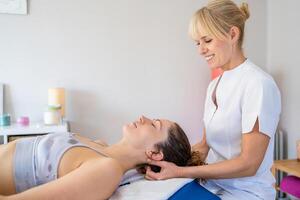 Cheerful female osteopath treating patient in hospital photo