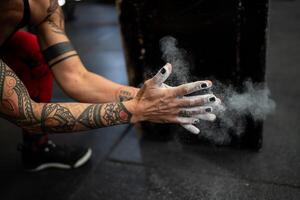 manos con magnesio abrochando Listo a levantamiento de pesas en un gimnasio foto