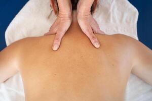 Masseuse kneading shoulders of woman in spa salon photo