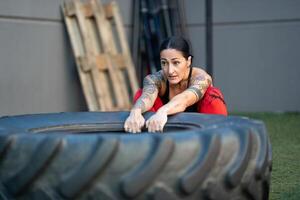 Strong woman about to flip a tire in the gym photo