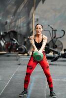 Woman performing kettlebell swing exercise in a gym photo