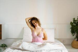 Happy woman doing stretching exercise on bed photo