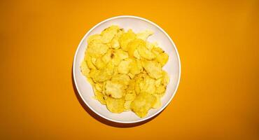 Close-up of potato chips or crisps in bowl against yellow background photo