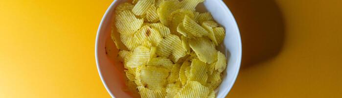 Close-up of potato chips or crisps in bowl against yellow background photo