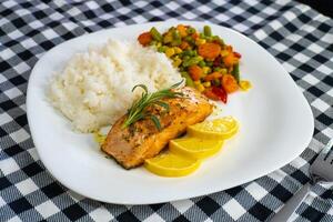 Fried salmon steak with lemon rice and vegetables photo