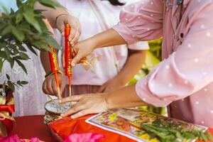 Kamphaeng Phet Thailand 14 Jan 2022, Hands of family helping to put red auspicious candles in pots in preparation for wedding ceremony of the bride to the groom's house. Traditions of overseas Chinese photo