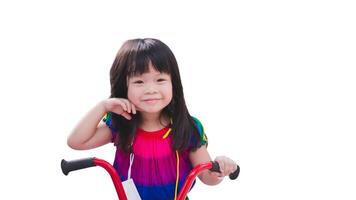 Cheerful Child on a Red Tricycle. A smiling young girl with bangs enjoying her ride on a bright red tricycle, isolated on white background. Asian Kid aged 3 years old. photo