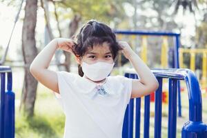 Portrait child wear face mask while at playground. Prevent spread of respiratory virus and problem of small toxic particulate matter PM2.5 air pollution. Empty space to enter text. photo