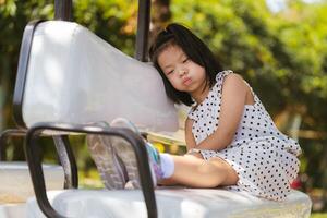 Young Girl aged 6 years old Daydreaming in Park, Thoughtful Kid rests her cheek on backrest cushion while sitting in a golf cart, seemingly lost in daydreams amidst the tranquility of a sunlit park. photo