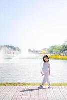 niña en polca puntos caminando por soleado frente al mar, niño toma agraciado caminar a lo largo el frente al mar, con el brillante Brillo Solar mejorando el alegre atmósfera de animado parque. vertical imagen.niño años 6 6 años. foto