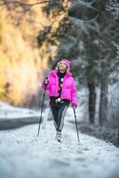 mujer practicando nórdico caminando en congelado la carretera foto