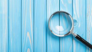 AI generated Magnifying glass on vibrant blue wooden texture photo