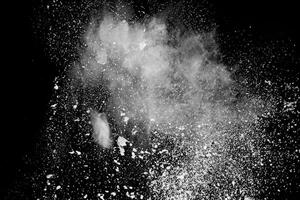 extrañas formas de nube de explosión de polvo blanco sobre fondo negro.salpicaduras de partículas de polvo blanco. foto