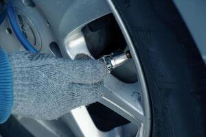 Bratislava, Slovakia - 01.12.2024 Hand holds the pressure gauge and fills the car tires with air. Car maintenance. photo