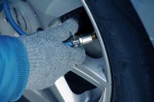 Bratislava, Slovakia - 01.12.2024 Hand holds the pressure gauge and fills the car tires with air. Car maintenance. photo