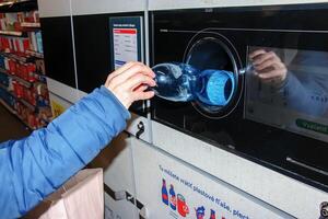 nitra, Eslovaquia - 16.01.2024 de cerca de un del hombre mano poniendo un botella dentro un residuos reciclaje máquina. foto