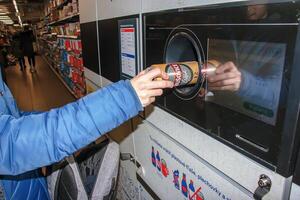 nitra, Eslovaquia - 16.01.2024 de cerca de un del hombre mano poniendo un botella dentro un residuos reciclaje máquina. foto