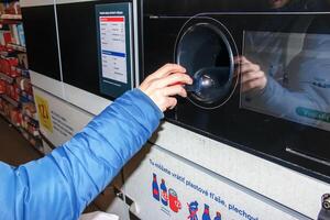 Nitra, Slovakia - 01.16.2024 Close-up of a man's hand putting a bottle into a waste recycling machine. photo