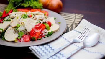 Spicy Glass Noodle Salad with Vietnamese Sausage  served in a gray plate Put on a wooden table and various vegetables. photo