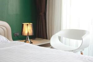 The bedroom is decorated with lamps, chairs and green walls with thin curtains to block the light. photo