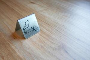 No Smoking symbol on a metal block on a wooden surface. Close-up. photo