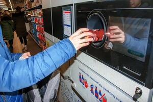 nitra, Eslovaquia - 16.01.2024 de cerca de un del hombre mano poniendo un botella dentro un residuos reciclaje máquina. foto