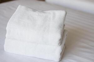 Selective focus on white fresh towels in hotel bed. Room service concept. Closeup white on new bedding and personal hygiene items. photo