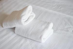 Stack of white towels on bed in hotel photo