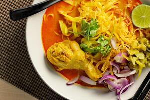 Khao soy Recipe, Curried Noodle Soup with Chicken Served on white Bowl, Thai Food, Curry Noodle, Thai Noodle, Northern Food. photo