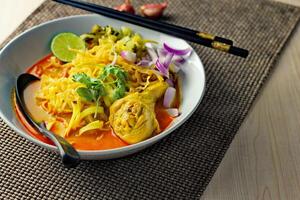 Khao soy Recipe, Curried Noodle Soup with Chicken Served on white Bowl, Thai Food, Curry Noodle, Thai Noodle, Northern Food. photo