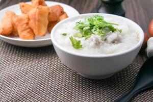 Hot Chinese porridge rice porridge with minced pork meatballs for breakfast on a wooden table. photo