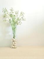 White stones in glass vase on wood table and white wall background photo