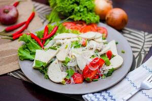 picante vaso fideos ensalada con vietnamita salchicha servido en un gris plato poner en un de madera mesa y varios vegetales. foto