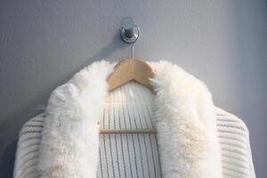 White fur coat hanging on the clothes hanger, closeup of photo
