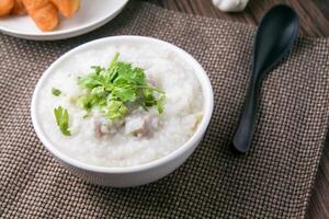 Hot Chinese porridge rice porridge with minced pork meatballs for breakfast on a wooden table. photo