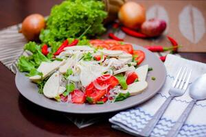 Spicy Glass Noodle Salad with Vietnamese Sausage  served in a gray plate Put on a wooden table and various vegetables. photo