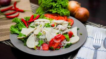 picante vaso fideos ensalada con vietnamita salchicha servido en un gris plato poner en un de madera mesa y varios vegetales. foto