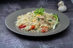 fried rice with chicken and vegetables in a plate on a dark background photo