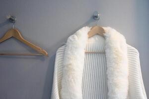 wooden clothes hanger with white fur on a white wall background photo