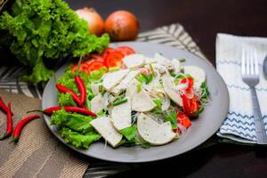 picante vaso fideos ensalada con vietnamita salchicha servido en un gris plato poner en un de madera mesa y varios vegetales. foto