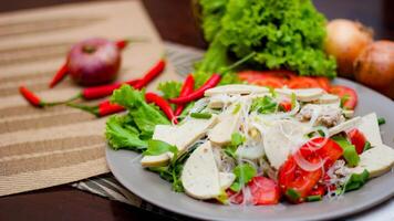 Spicy Glass Noodle Salad with Vietnamese Sausage  served in a gray plate Put on a wooden table and various vegetables. photo