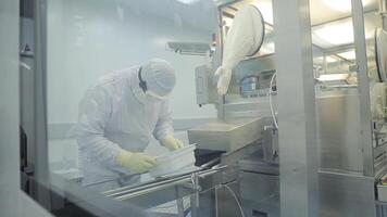 Pharmaceutical industry. Male factory worker inspecting quality of pills packaging in pharmaceutical factory. Automatic tape to create packaging and filling of medicines. control in the factory of video