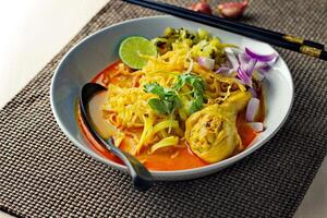 Khao soy Recipe, Curried Noodle Soup with Chicken Served on white Bowl, Thai Food, Curry Noodle, Thai Noodle, Northern Food. photo