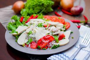 Spicy Glass Noodle Salad with Vietnamese Sausage  served in a gray plate Put on a wooden table and various vegetables. photo