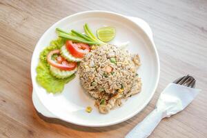 Pork fried rice served in a restaurant with wooden floor tables with tomatoes, cucumbers, scallions, fried rice, delicious food made from steamed rice. photo