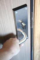 Hand opening a door with a keyhole in a hotel room. photo